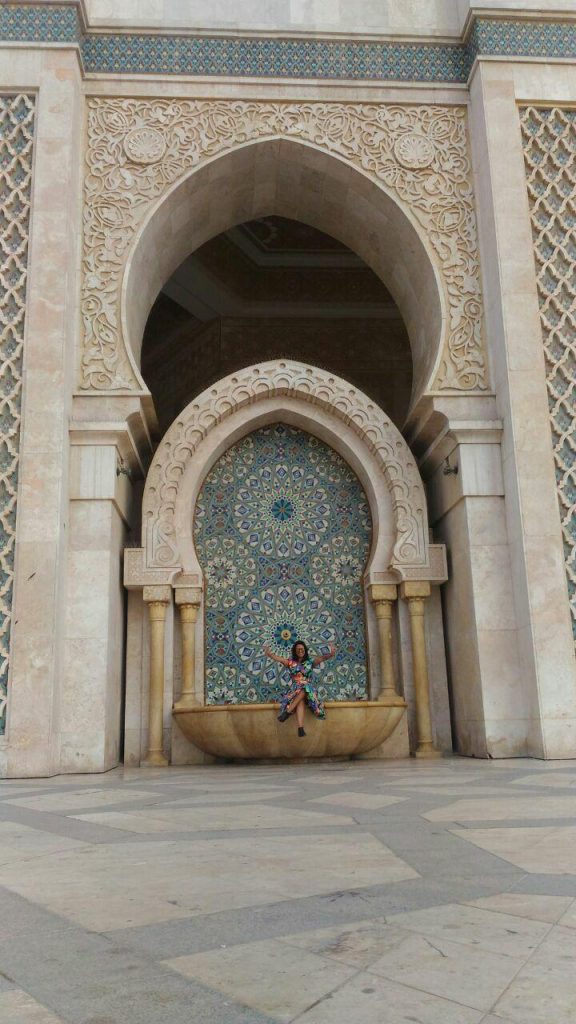 Picture of me wearing a colourful dress, sitting on a fountain at the Hassan Mosque II, in Casablanca, Morocco.

Foto de mim usando um vestido colorido, sentada em uma fonte na Mesquita Hassan II, em Casablanca, Marrocos.
