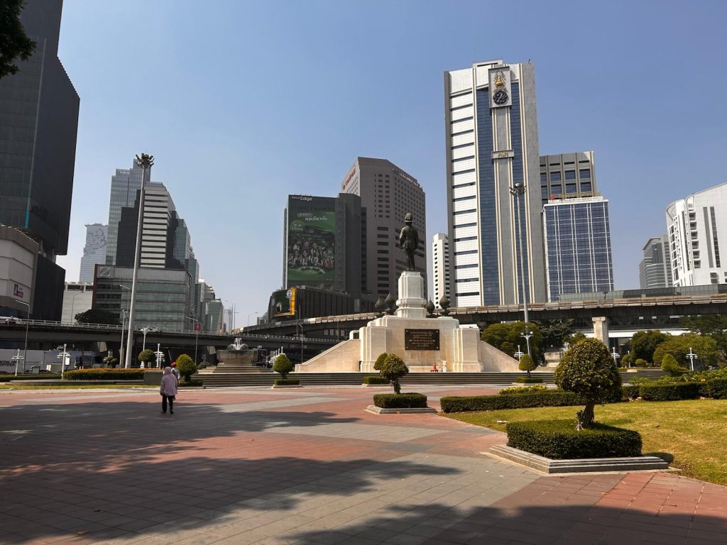 Picture of a park in Bangkok, with tall buildings mixed into a green scenery. Imagem de um parque em Bangkok, com prédios altos se misturando a uma paisagem verde.