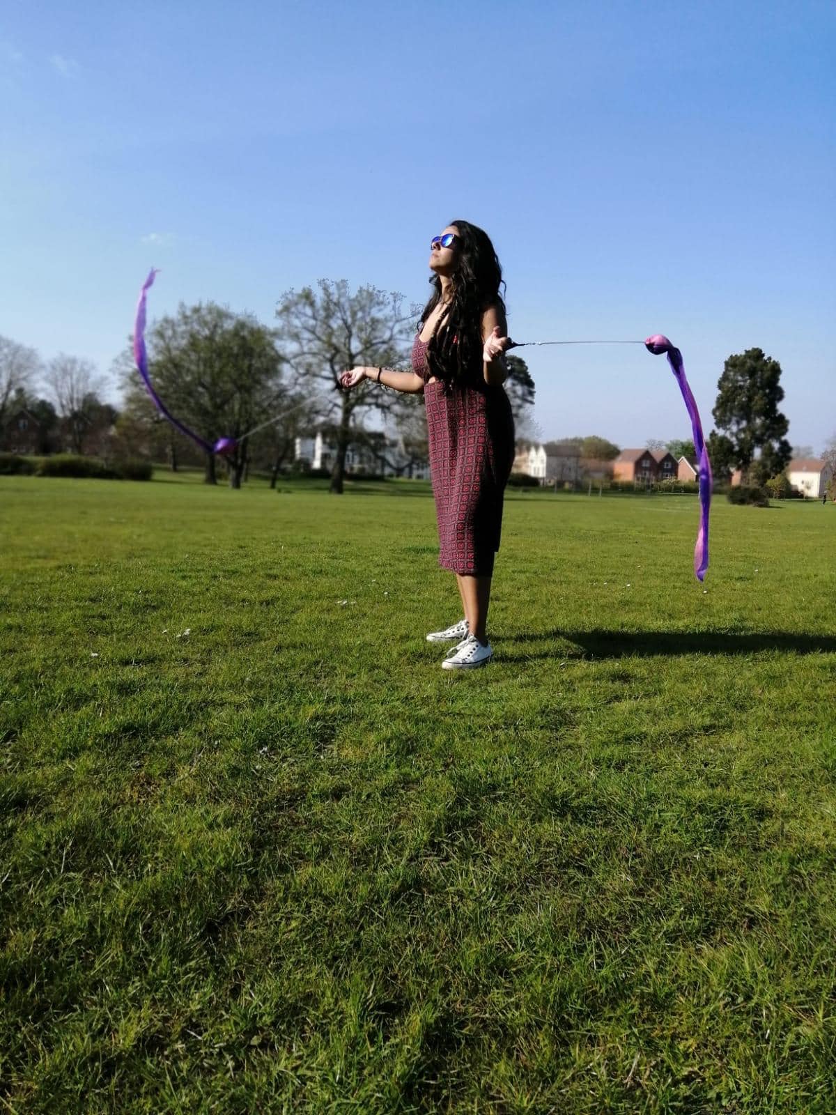 Photo of me wearing a burgundy dress and practising swing poi in a park in Bracknell, England. Foto minha usando um vestido bordô e praticando swing poi em um parque em Bracknell, Inglaterra.