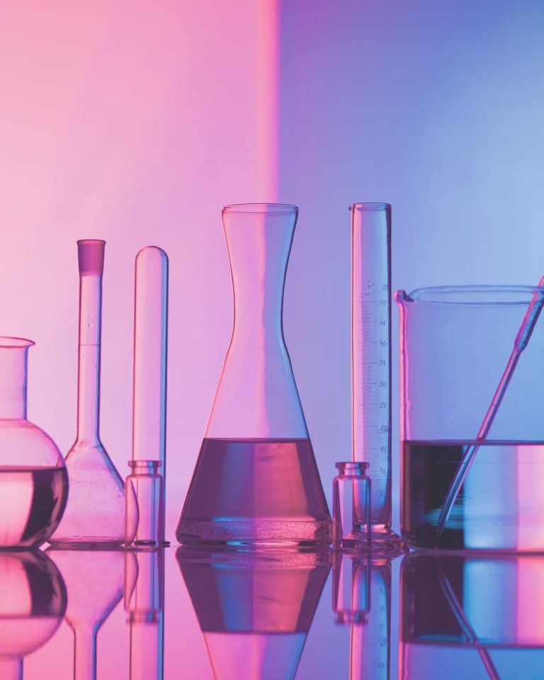 Pink and purple photo of seven laboratory flasks, illustrating the science-backed benefits of travelling solo.